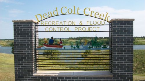Sign for Dead Colt Creek Recreation & Flood Control Project, featuring a scenic view of water and greenery.