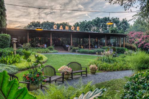 A scenic view of a restaurant named "Canoe" surrounded by lush greenery and outdoor seating.