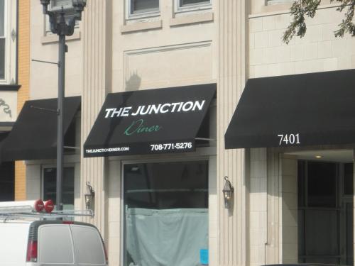 Sign for "The Junction Diner" with a phone number and website, located on a storefront with black awnings.