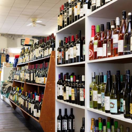 A well-stocked wine shop featuring shelves filled with various bottles of red, white, and rosé wines.