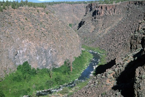 A winding river flows through a deep canyon surrounded by rocky cliffs and lush greenery.