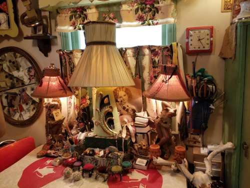 A cozy room filled with eclectic decor, including lamps, vintage items, and a colorful tablecloth.