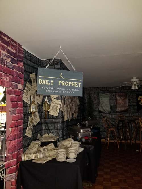 A themed room featuring a "Daily Prophet" sign, newspaper decor, and tables set for an event.