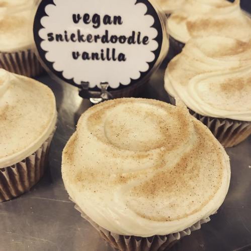 Vegan snickerdoodle vanilla cupcakes with swirled frosting and a sprinkle of cinnamon.