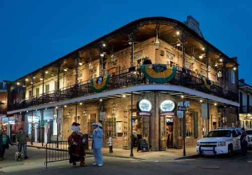 Historic building with a balcony, decorated for a festival, bustling street scene at dusk.