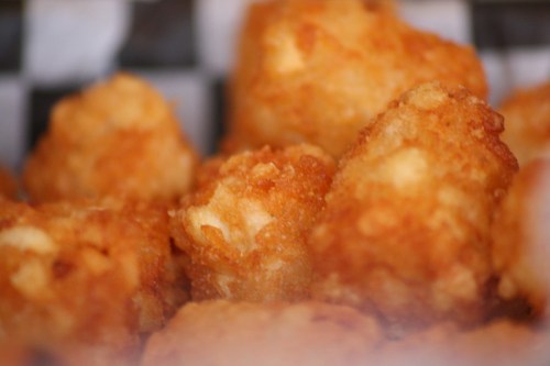 A close-up of golden-brown, crispy tater tots piled together in a basket.