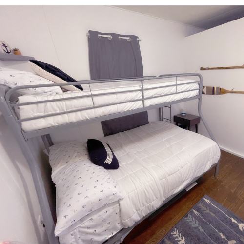 A cozy bedroom featuring a gray bunk bed with white bedding and a small nightstand beside it.