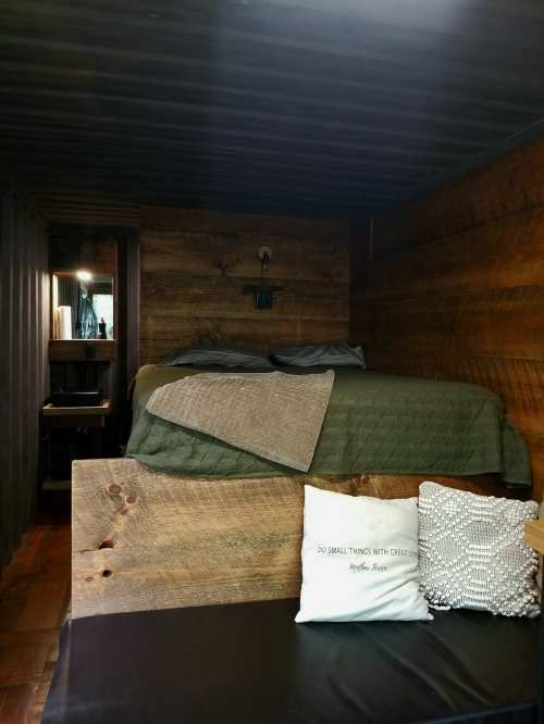 Cozy interior of a tiny home with a wooden bed, decorative pillows, and a warm, rustic atmosphere.