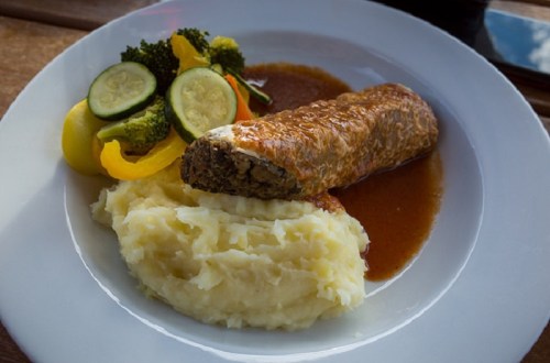 A plate featuring a rolled meat dish with gravy, creamy mashed potatoes, and a side of mixed vegetables.