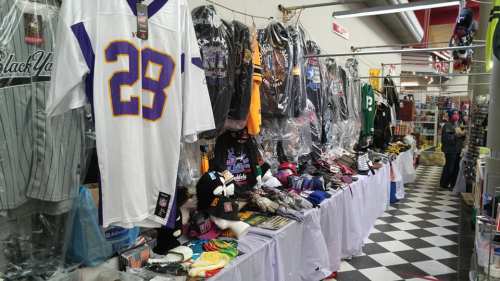 A display of various sports jerseys, hats, and merchandise in a market setting.