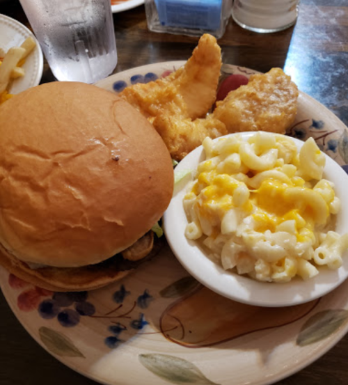 A plate with a burger, fried chicken, and a side of macaroni and cheese.