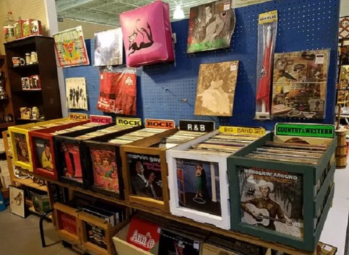 A display of vinyl records organized by genre, including rock, R&B, and country, in a vintage shop setting.