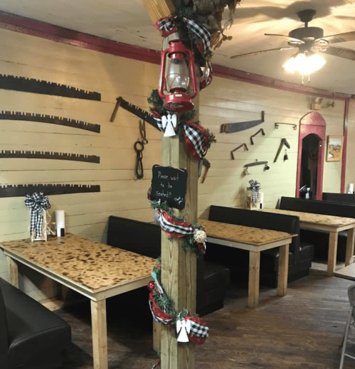 Cozy restaurant interior with wooden tables, festive decorations, and a vintage lantern on a decorated post.