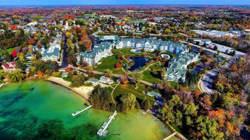 Aerial view of a lakeside resort surrounded by colorful autumn trees and a clear blue lake.