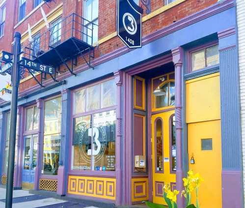 Colorful storefront with purple and yellow accents, featuring large windows and a prominent "3" sign above the entrance.