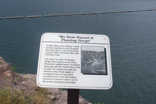 Sign about Flaming Gorge, detailing its history and geological significance, with a view of the water in the background.
