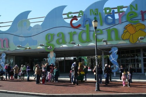 Colorful entrance to Camden Children's Garden, with families and children gathered outside on a sunny day.