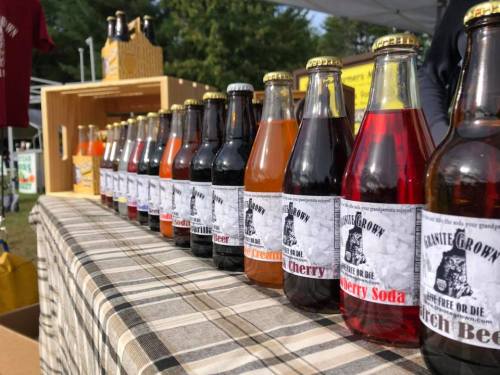 A row of colorful soda bottles on a table, featuring various flavors with vintage-style labels.