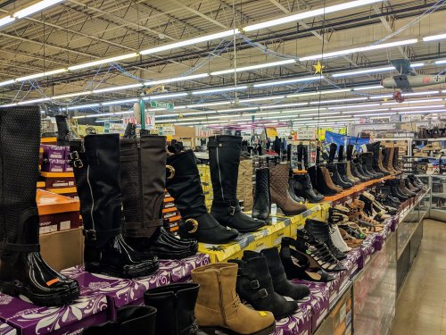 A display of various styles of boots and shoes arranged on shelves in a retail store.
