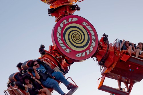 A thrilling amusement park ride spins upside down, with excited riders hanging on as they experience the rush.
