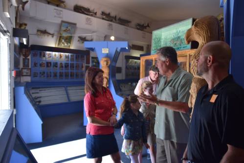 A group of people engages in conversation inside a museum, surrounded by exhibits and displays.