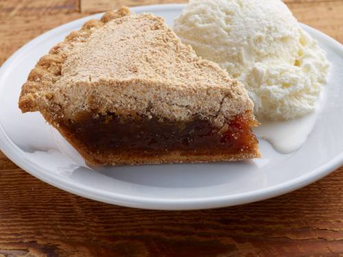 A slice of pie with a crumbly topping served on a plate alongside a scoop of vanilla ice cream.