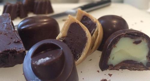 An assortment of chocolate candies, including dark chocolate and filled varieties, on a white surface.