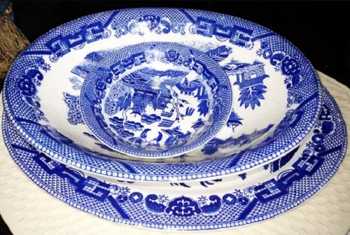 Three blue and white patterned ceramic bowls stacked together, featuring intricate designs of landscapes and floral motifs.
