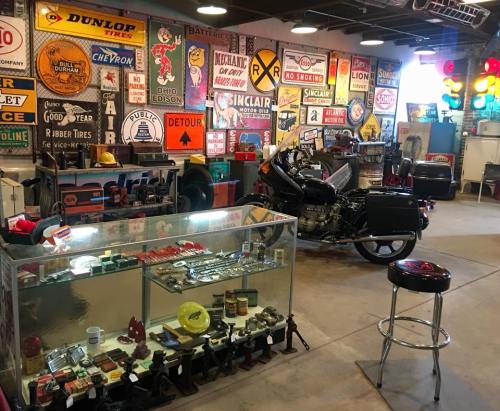 A vintage garage filled with old signs, tools, and a motorcycle, showcasing a nostalgic automotive atmosphere.