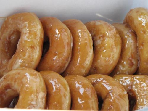 A box filled with glazed donuts, showcasing their shiny, golden-brown surface.