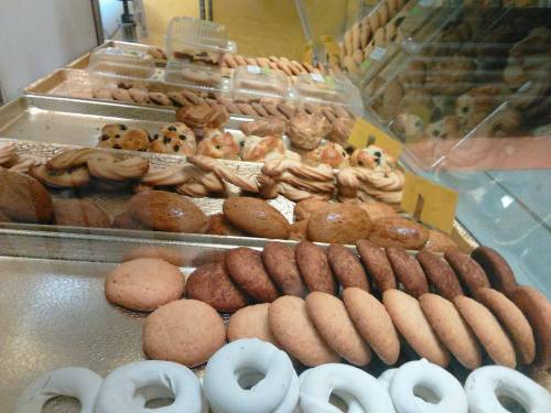 A display of various baked goods, including cookies, pastries, and donuts, arranged on trays.