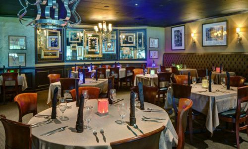 Elegant restaurant interior with neatly set tables, soft lighting, and decorative wall art.