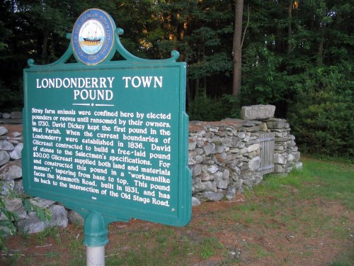 A green historical sign for Londonderry Town Pound, surrounded by trees and stone walls, detailing its history.
