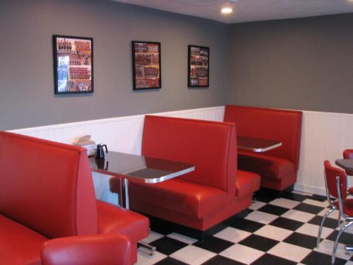 Cozy diner interior featuring red booths, a checkered floor, and framed photos on the wall.