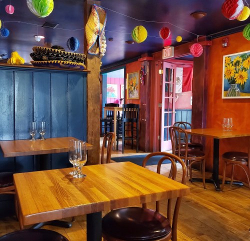 Cozy restaurant interior with wooden tables, colorful decorations, and vibrant wall art.