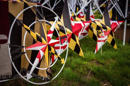 Colorful star decorations in red, yellow, and black, displayed on a grassy area at an outdoor event.