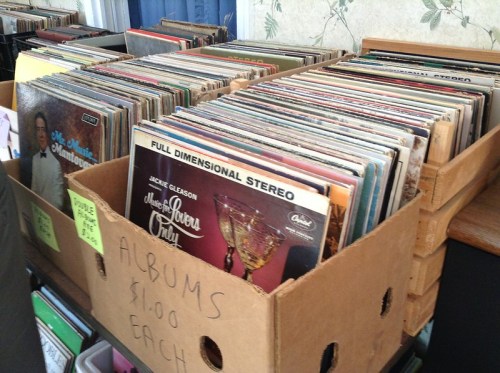 A box filled with vinyl records, labeled "Albums $1.00 each," showcasing various album covers.