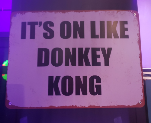 Sign with bold text reading "IT'S ON LIKE DONKEY KONG" against a colorful background.