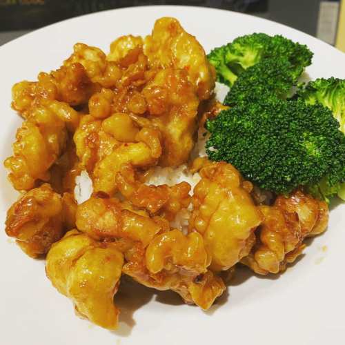 A plate of orange chicken served over rice, accompanied by steamed broccoli.