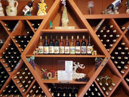 A wooden wine rack displaying various bottles of wine, with decorative elements and a menu on a shelf.