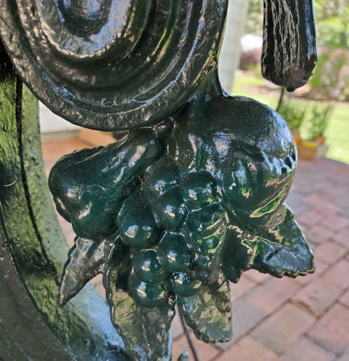 Close-up of a decorative green metal design featuring grapes and leaves.