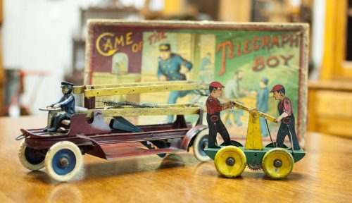 A vintage toy fire truck and a mechanical toy with two figures, set against a colorful game box background.