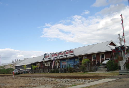A seafood restaurant with a metal roof, located near train tracks under a cloudy sky.