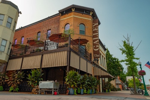 Historic building with a sign reading "The Galley," featuring outdoor seating and lush greenery.