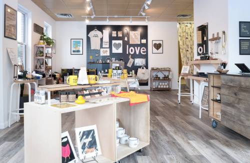 A cozy shop interior featuring various handmade items, wall art, and colorful merchandise displayed on wooden shelves.