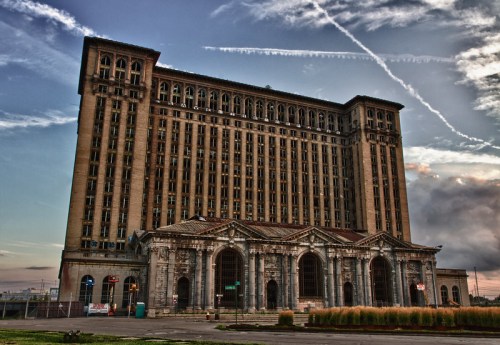 Abandoned historic train station with a tall, ornate building and a cloudy sky in the background.