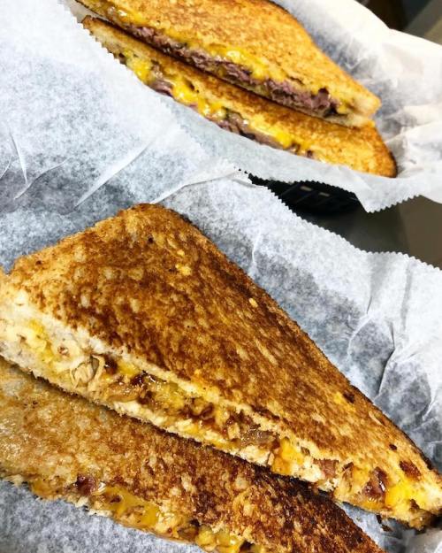 Two golden-brown grilled cheese sandwiches with melted cheese, served on parchment paper.