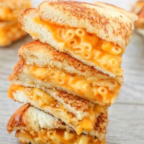 A stack of grilled cheese sandwiches filled with macaroni and cheese, showcasing golden, crispy bread and gooey filling.