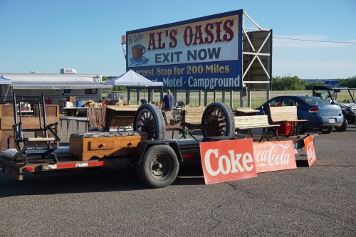 A trailer loaded with vintage furniture and signs parked in front of a roadside motel and campground.