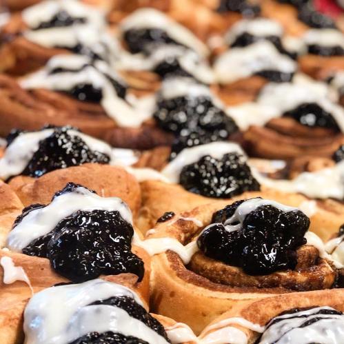 Close-up of cinnamon rolls topped with blackberries and drizzled with white icing.